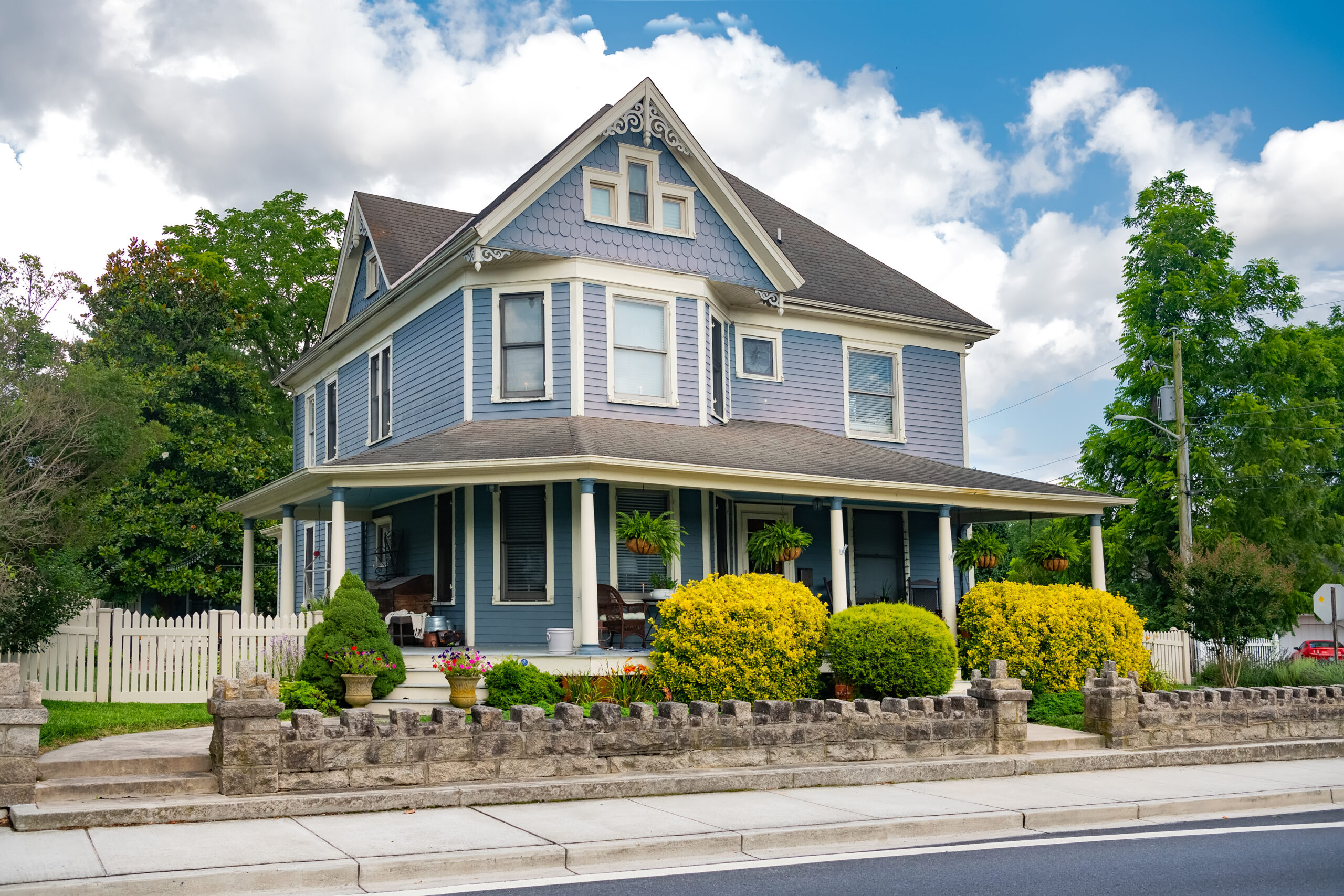 big classic American two-level house with terrace. Lawn and shrubs in the front yard.