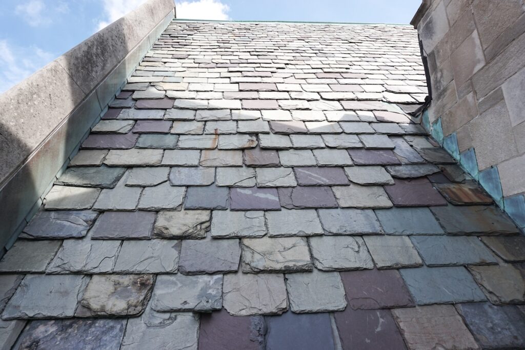 Weathered slate tiles on the roof of a historic building. Slate is highly valued as a traditional building material.
