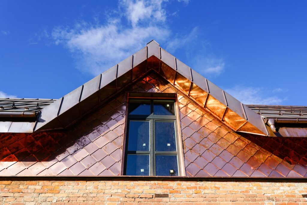 a fragment of a house facade and roof covered with copper plates