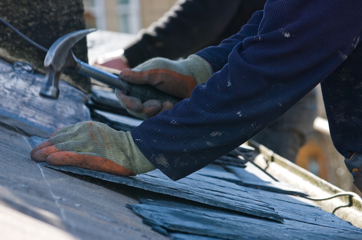 Roofers replacing roof on home with slate tiles