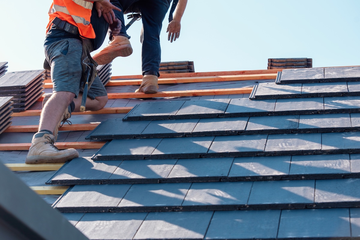 Skilled workers installing roofing tiles
