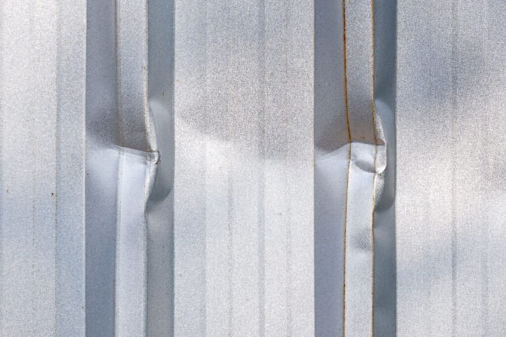 Close up dents on surface of corrugated metal roof