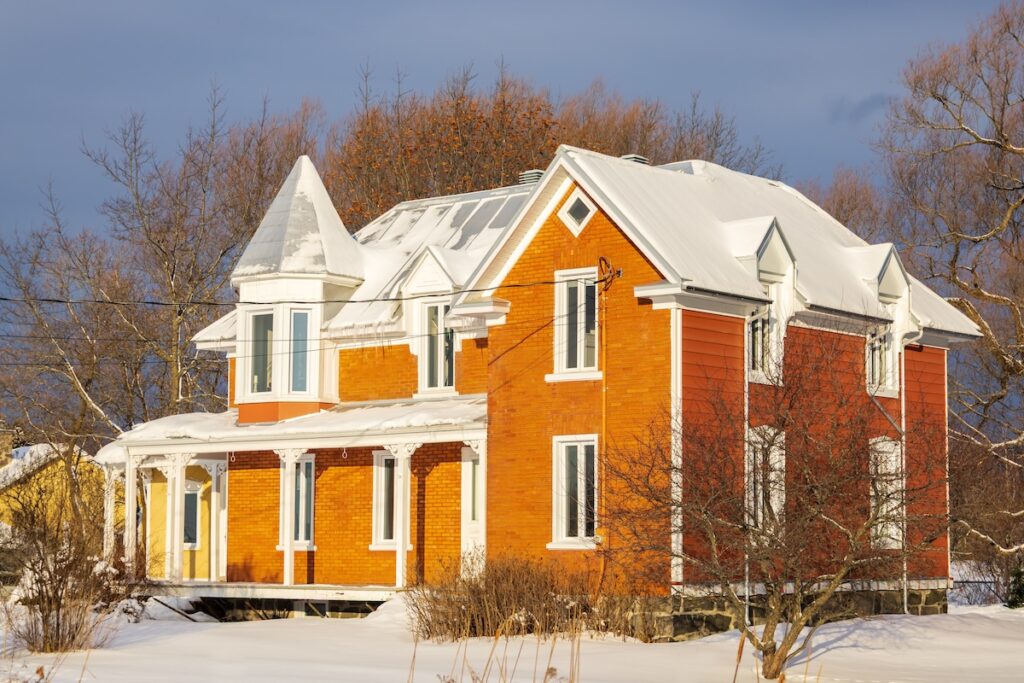 Beautiful red brick and clapboard siding Victorian style house with metal roof